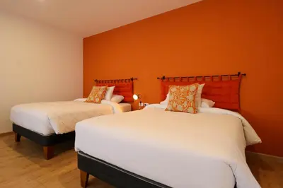 two beds in a room with orange walls at Casa Muru By Wynwood House in Cusco