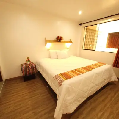 a bedroom with a large white bed with a window at Hotel Ruta Amazónica Machupicchu in Machu Picchu