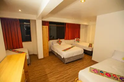 a hotel room with two beds and red curtains at Hotel Ruta Amazónica Machupicchu in Machu Picchu