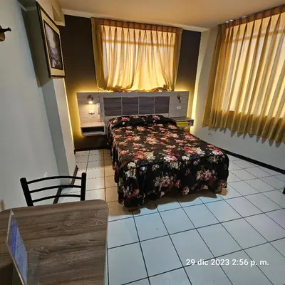 a bedroom with a bed and a table and chair at Hostal La Cascada in Lima