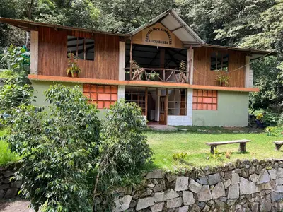 a house with a bench in front of it at Eco Inca Trail Lodge Lucmabamba in Cusco