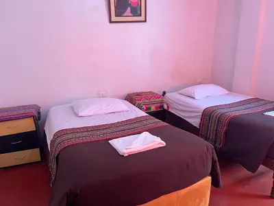 two beds in a room with pink walls at Eco Inca Trail Lodge Lucmabamba in Cusco