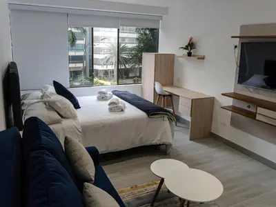 a bedroom with a bed and a couch and a tv at Moderno 2BR Center Miraflores- Balta 301 in Lima