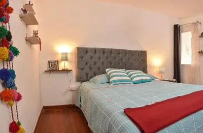 a bedroom with a blue bed with a gray headboard at Apu House Minidepartamento in Cusco