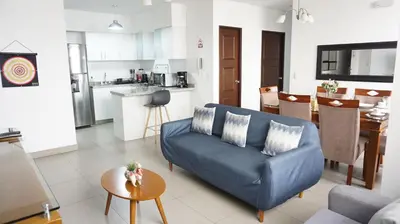 a living room with a blue couch and a kitchen at APARTAMENTOS PRIVADOS Lima Airport Perú in Lima
