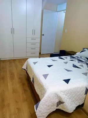 a bedroom with a bed and white cabinets at Departamento cómodo y cálido in Lima