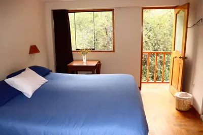 a bedroom with a blue bed and a window at Full Moon Eco Lodge in Ollantaytambo