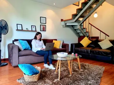 a woman sitting on a couch with a laptop at DuplexTOP Miraflores Queen SmartTV Lima 1B 101 in Lima