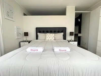 a large white bed with two towels on it at Departamento con vista de Lima in Lima