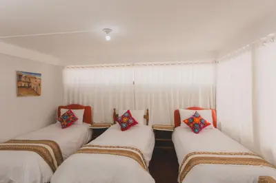 a room with three beds with colorful pillows on them at Lucios Cusco in Cusco