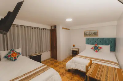 a bedroom with two beds and a window at Lucios Cusco in Cusco