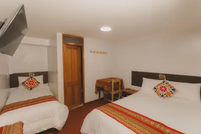 a bedroom with two beds and a tv and a table at Lucios Cusco in Cusco