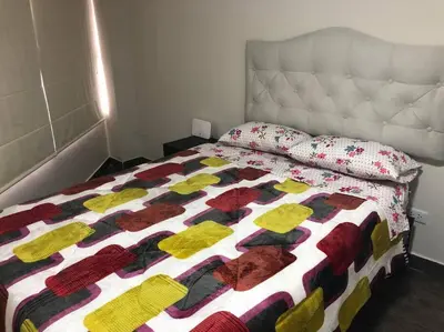 a bed with a colorful blanket and pillows on it at Mini Apartamento, cerca al Malecón de Chorrillos in Lima