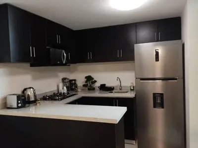 a kitchen with black cabinets and a stainless steel refrigerator at Mini Apartamento, cerca al Malecón de Chorrillos in Lima