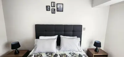 a bedroom with a black headboard and white pillows at Departamento de Estreno en Miraflores in Lima