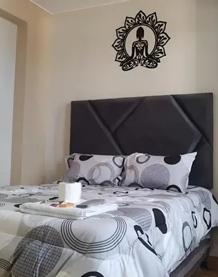 a bedroom with a bed with a black and white comforter at Hospedaje Mónaco - Jauja Airport in Jauja