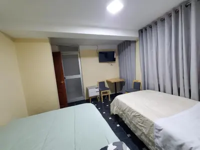 a hotel room with two beds and a table and chair at Jebas House in Cusco