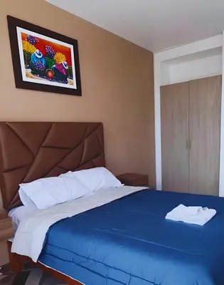 a bedroom with a blue bed with a picture on the wall at Hospedaje Mónaco - Jauja Airport in Jauja