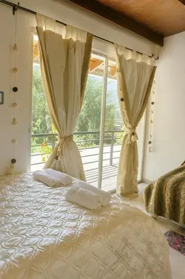 a bedroom with a bed and a large window at La Casita de Orfi in Calca