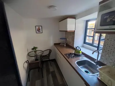 a small kitchen with a sink and a table at Mini Apart I - Sumaq Wasi Alba in Cusco