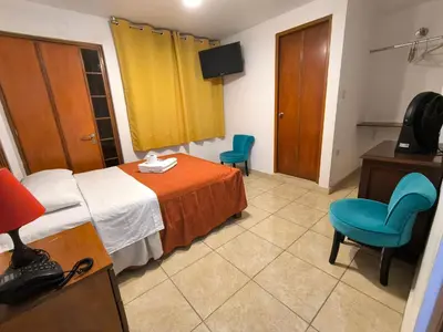 a hotel room with a bed and two chairs at El Paraíso de Lunahuaná in Lunahuaná