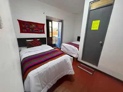 a room with two beds and a door with a window at Mallku Wasi - Lodging Hotel Cusco in Cusco