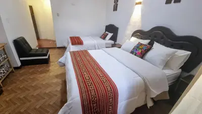 a hotel room with two beds and a chair at Mallku Wasi - Lodging Hotel Cusco in Cusco