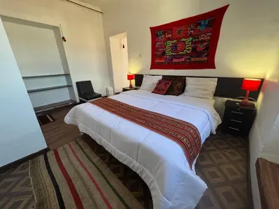 a bedroom with a large bed with a red painting on the wall at Mallku Wasi - Lodging Hotel Cusco in Cusco