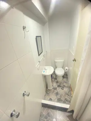 a white bathroom with a toilet and a shower at Casa Medina Hostal in Cusco