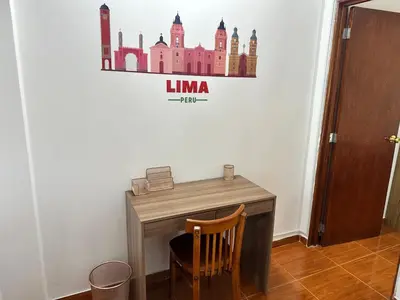 a desk with a chair and a sign on a wall at Bello depa San Miguel 3 camas 2 tv smart terraza in Lima