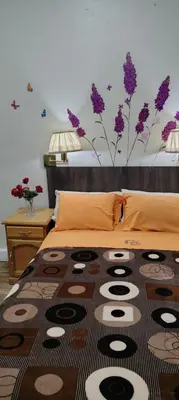 a bedroom with a bed with purple flowers on the wall at Hospedaje CASA REAL in Huancayo