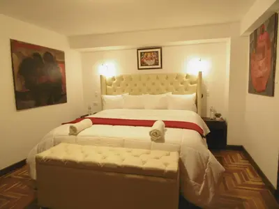 a bedroom with a large bed with a bench in it at Hotel Montecristo Cusco in Cusco