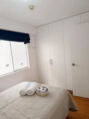 a bedroom with a bed with towels and cabinets at Apartamento moderno y céntrico en Lima, 3 Dormitorios in Lima