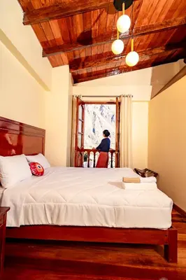 a bedroom with a bed and a person looking out the window at NUNA SUMAQ Hotel in Ollantaytambo