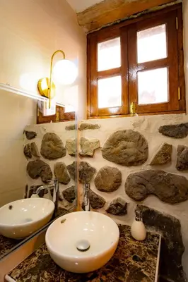 a bathroom with two sinks and a stone wall at NUNA SUMAQ Hotel in Ollantaytambo