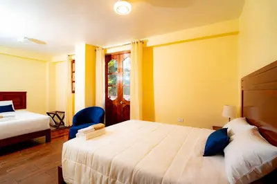 a bedroom with a large bed and a blue chair at NUNA SUMAQ Hotel in Ollantaytambo