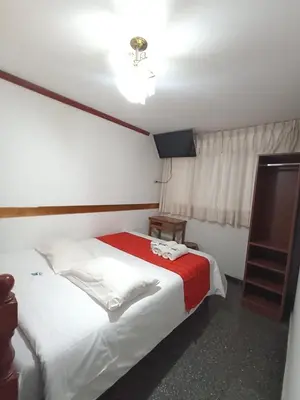 a bedroom with a bed with a red and white blanket at Hostal Cielo Azul in Canta
