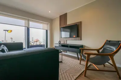a living room with a couch and a television and a chair at Liven in Miraflores by Wynwood House in Lima