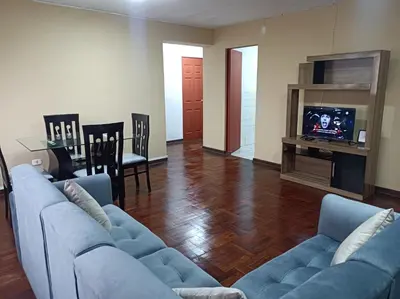 a living room with a blue couch and a television at Alojamientos Perú II in Lima