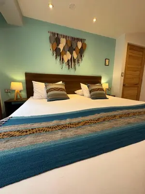 a bedroom with a large bed with logs on the wall at CASA CRISTOBAL Centenario in Cusco
