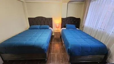 two beds in a bedroom with blue pillows at Casa Independiente muy cerca al centro historico - Los Profesionales in Cusco