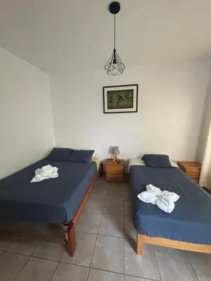 a room with two beds and a picture on the wall at Ravenala Paracas Hostel & Apartment in Paracas