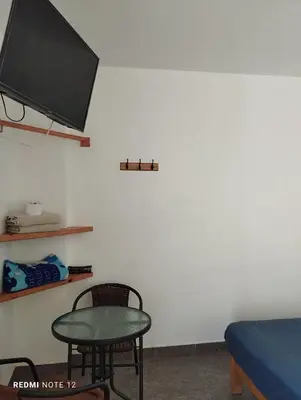 a room with a table and a tv on a wall at Ravenala Paracas Hostel & Apartment in Paracas