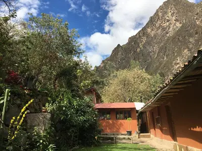 a building with a mountain in the background with trees at HOSTEL INKA PACCHA - cascada inka in Ollantaytambo