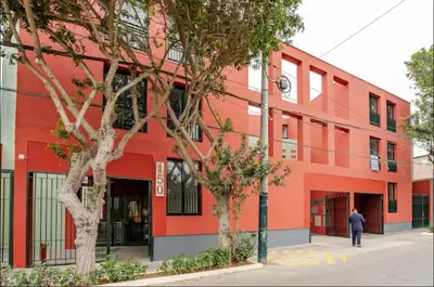 a man walking in front of a red building at Cómodo y silencioso Apartamento 1BR en Barranco in Lima