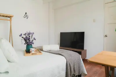 a white bedroom with a bed and a tv at Casa Bellido - Miraflores Private Rooms - Cocina Compartida - Wifi in Lima