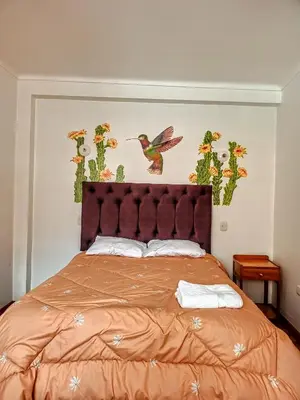 a bedroom with a bed with a bird on the wall at Sequeiros Garden in Ollantaytambo