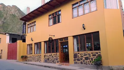 a yellow building with windows on a street at Sequeiros Garden in Ollantaytambo