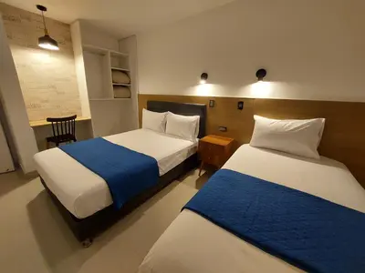 a bedroom with two beds with blue and white sheets at Mandala Lux Hotel in Pisco