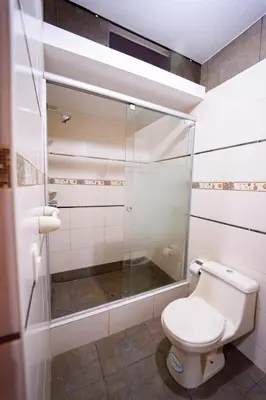 a bathroom with a toilet and a glass shower at Hostal Los Balcones in Nazca